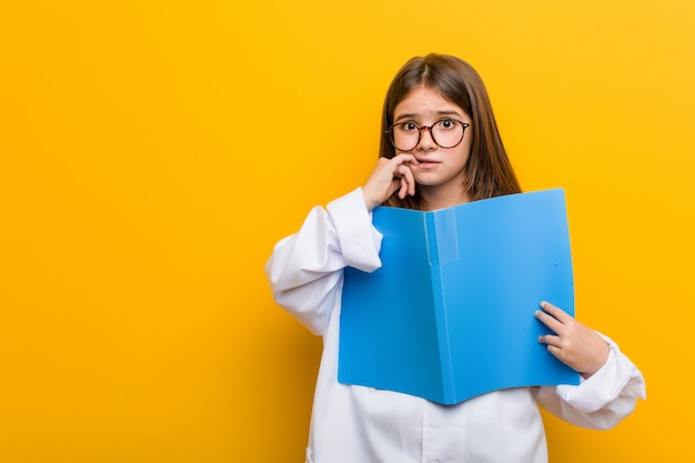 Kleine kaukasische Frau, die beißende Fingernägel eines Doktorkostüms, nervös und sehr besorgt trägt.