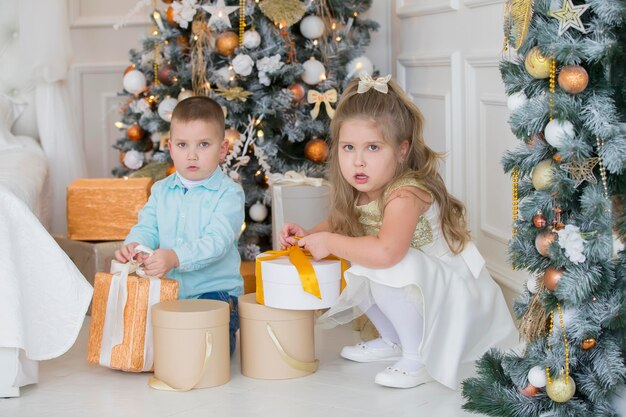 Kleine Kinder am Weihnachtsbaum mit Geschenken