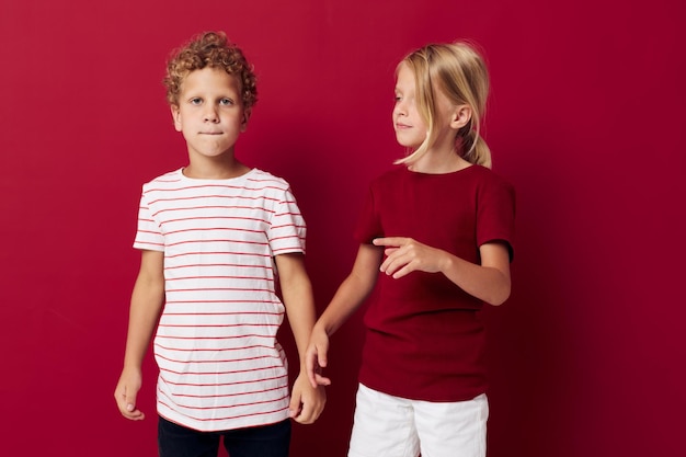 Kleine Kinder-Emotionen stehen unverändert nebeneinander in Alltagskleidung auf rotem Grund