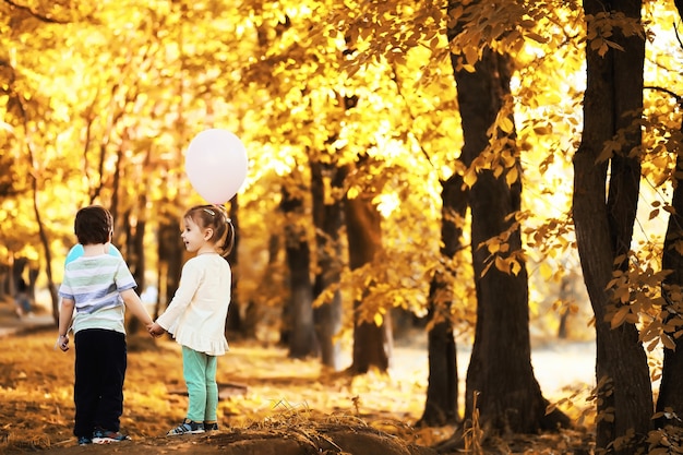 Kleine Kinder gehen im Herbstpark spazieren