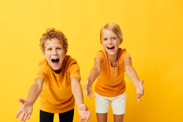 Kleine Kinder in gelben T-Shirts, die nebeneinander stehen, Kindheitsgefühle, isolierter Hintergrund unverändert