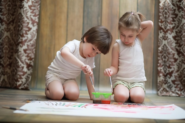 Kleine Kinder malen auf einem großen Blatt Papier
