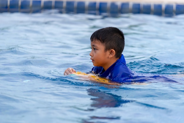 Kleine Kinder schwimmen im Schwimmbad mit Kick-Board.