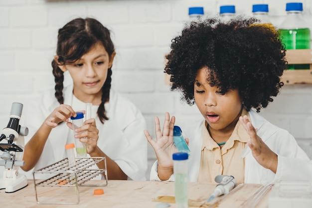 Kleine Kinder spielen aufregend mit Chemie-Wissenschafts-Kits im Schulklassenzimmer mit einem Klassenkameraden