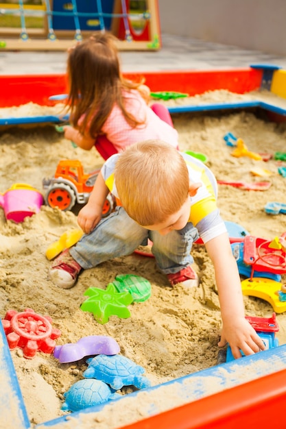 Kleine Kinder spielen mit Sand auf dem Spielplatz.