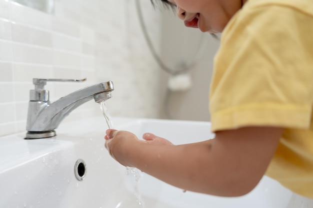 Kleine Kinder waschen sich die Hände mit Seifenblasen und spülen sie mit klarem Wasser ab, um die Ausbreitung von Keimen nach dem Back-to-Home-Virus oder Covid19 zu verhindern und zu stoppen. Gute Gesundheit und gute persönliche Hygiene, Virusbakterien