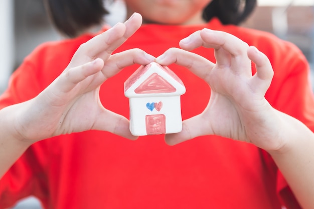 Kleine Kinderhände, die Haus halten