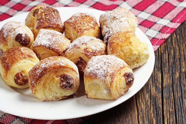 Kleine Kuchen mit Rosinen im Teller auf dem Tisch verdeckte rote Tischdecke