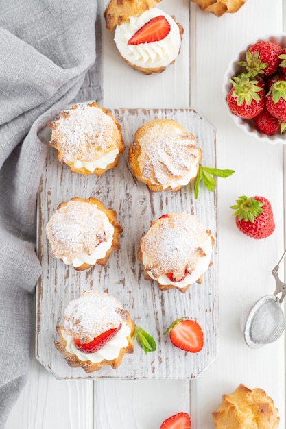 Kleine Kuchen Windbeutel Brandteig mit Pudding Erdbeere und Puderzucker Kopieren Sie Platz
