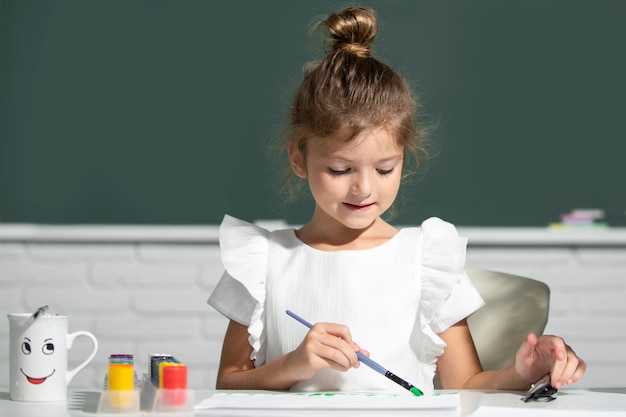 Kleine Mädchen, die bunte Bilder mit Buntstiften im Schulklassenzimmer malen, malen Kinder