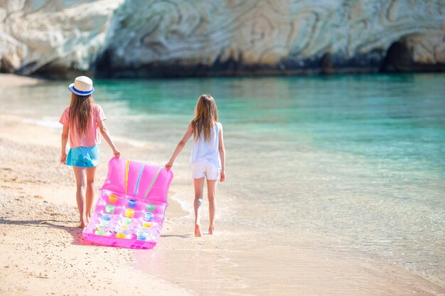 Kleine Mädchen, die Spaß am tropischen Strand haben, der zusammen am flachen Wasser spielt