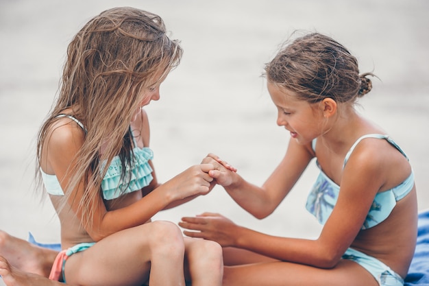 Kleine Mädchen, die Spaß am tropischen Strand zusammen spielt haben