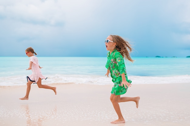 Kleine Mädchen, die Spaß haben, Ferien auf tropischem Strand zu genießen