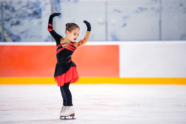 Kleine Mädchen Eiskunstläuferin in einem hellrosa Trainingsanzug mit einem Lächeln