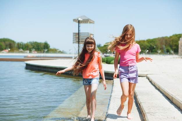 Kleine Mädchen haben Spaß am Stadtstrand, laufen auf dem Wasser am See