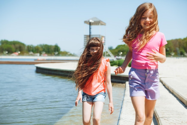 Kleine Mädchen haben Spaß am Stadtstrand, laufen auf dem Wasser am See