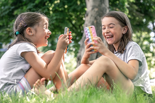 Kleine Mädchen im Freien mit Telefonen in einer Hülle mit Pickeln knallen es, ein trendiges Anti-Stress-Spielzeug.