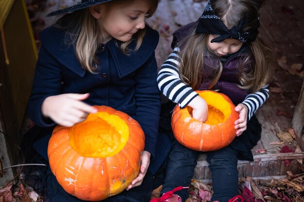 Kleine Mädchen machen Jackolantern aus großen Kürbissen zur Feier des Halloween-Urlaubs