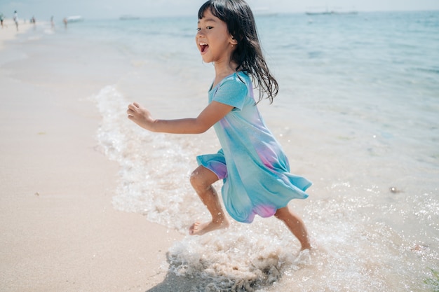 Kleine Mädchen rennen und lachen am Strand