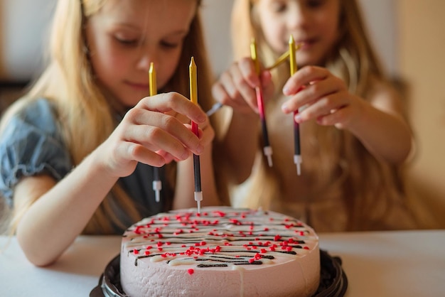 Kleine Mädchen, Schwestern, Zwillinge freuen sich, Geburtstagstorte mit Kerzen zu dekorieren