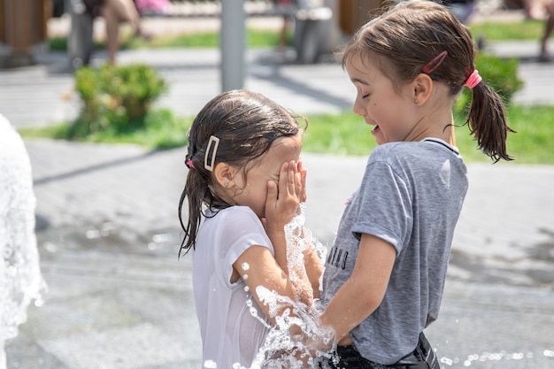 Kleine Mädchen spielen in einem Brunnen unter Wasserspritzern.