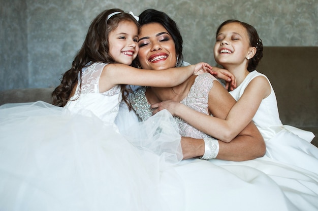 Kleine Mädchen umarmen die zarte Stellung der Braut im Raum