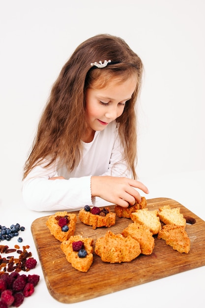 Kleine Mädchen Zeug Kuchen mit frischen Beeren.