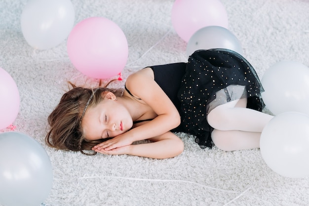Kleine müde Prinzessin, die nach aktiver Spielzeit schläft. glückliche sorglose Kindheit. süßes Mädchen schlief mitten in Luftballons ein.