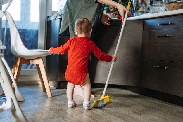 Foto kleine mütter helfer süßes kleinkind baby mädchen mit mopp helfen ihrer mutter hausarbeit in der küche