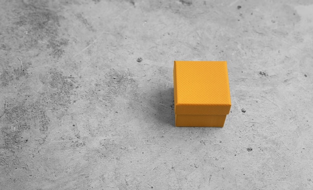 Kleine orangefarbene Geschenkbox auf hellem Betonhintergrund Platz für Text kopieren