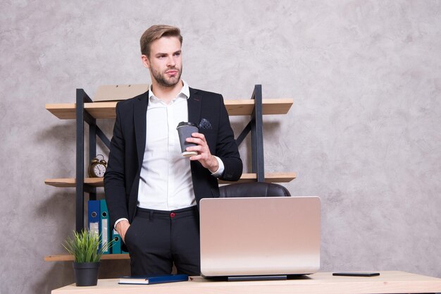 Kleine Pause zum Entspannen Kaufmann trinkt Kaffee Selbstbewusster Mann trinkt Kaffee Chef-Arbeitsplatz Schöner Mann im Geschäftsbüro Inspiriert von einer Tasse frischen Kaffee CEO-Hauptbüro-Konzept