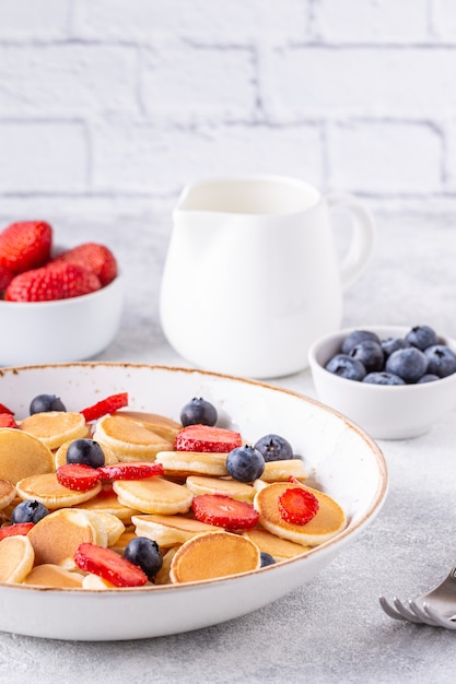 Kleine Pfannkuchen mit Erdbeeren und Blaubeeren zum Frühstück. Selektiver Fokus.