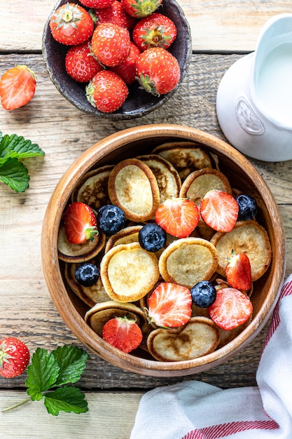 Kleine Pfannkuchen Müsli und Schokolade Mini Pfannkuchen in einer Holzschale mit Honig und Erdbeeren