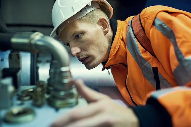 Kleine Probleme lösen, bevor sie zu großen Problemen werden Aufnahme eines jungen Ingenieurs, der mit komplizierten Maschinen arbeitet, während er Sicherheitsausrüstung trägt