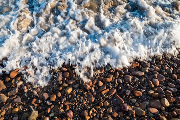 Kleine rote Kieselsteine, die von Wellen an einem Strand in Las Flores Maldonado Uruguay gewaschen werden