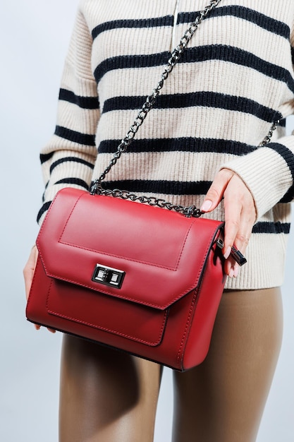 Kleine rote Ledertasche in einer weiblichen Hand auf weißem Hintergrund Umhängetasche Frau mit einer roten Handtasche Stil, Mode, Vintage und Eleganz