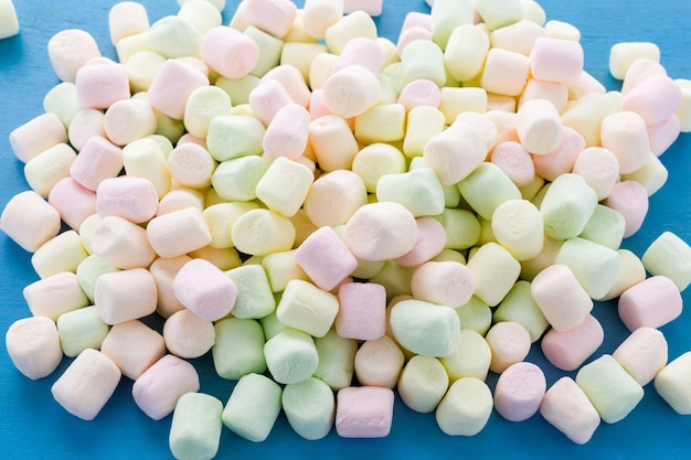 Kleine runde mehrfarbige Marshmallows auf blauem Hintergrund.