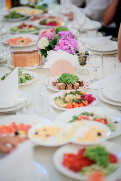 Kleine runde Teller mit schmackhaften Gerichten stehen auf einem langen Esstisch