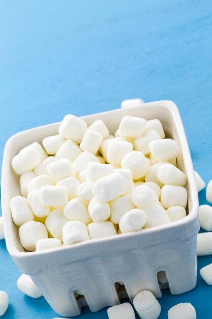 Kleine runde weiße Marshmallows auf blauem Hintergrund.