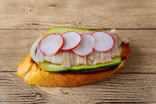 Kleine Sandwiches mit Gemüse, Fisch, Gurken, Zwiebeln, Rettich, Sandwich, Hering, hölzerne Hintergrundoberseite v