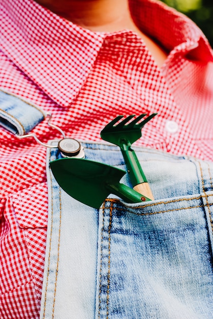 Kleine Schaufeln und Rechen in der Tasche des Overalls