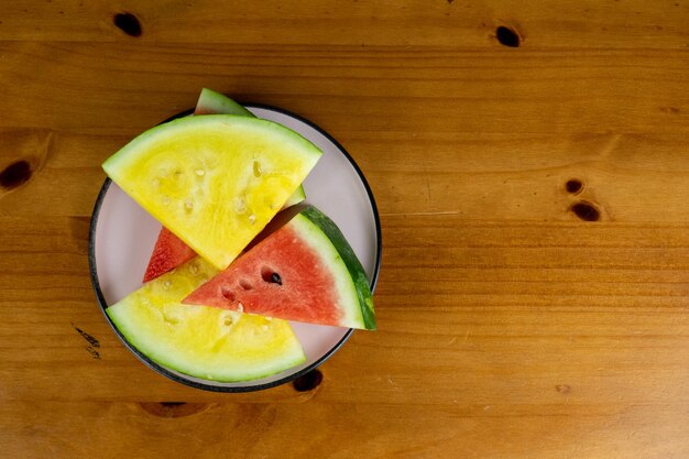 kleine Scheiben roter und gelber Wassermelone auf einem weißen Teller serviert von oben