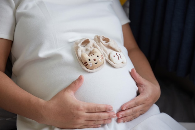 Foto kleine schuhe für das ungeborene baby im bauch der schwangeren frau