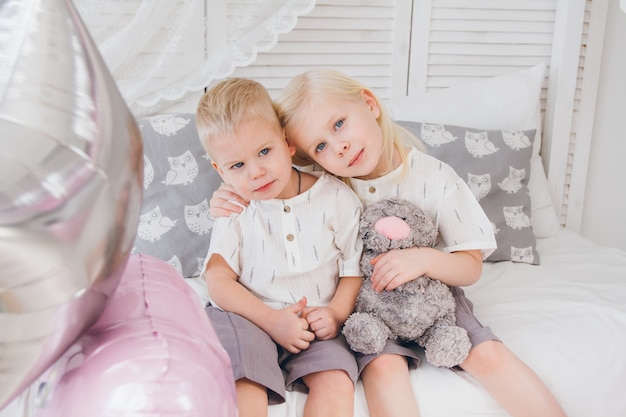 Kleine Schwester und Bruder sitzen auf dem Bett