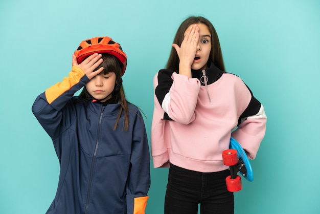 Kleine Schwestern, die Radfahren und Skater üben, isoliert mit Überraschung und schockiertem Gesichtsausdruck