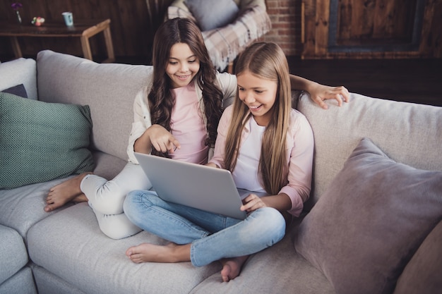 Kleine Schwestern posieren zusammen auf der Couch