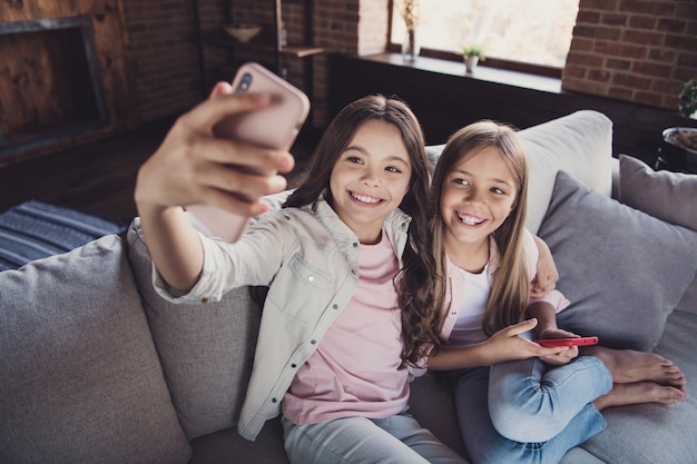 Kleine Schwestern posieren zusammen auf der Couch