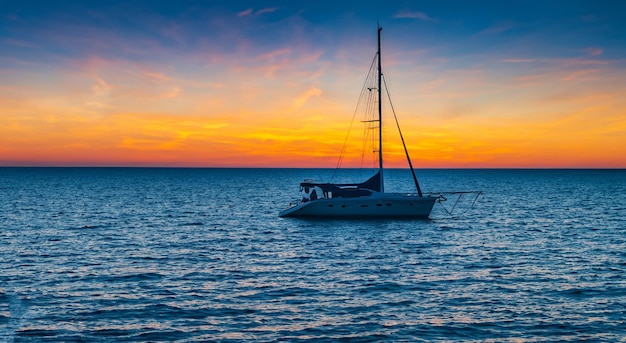 Kleine Segelboote, die bei Sonnenuntergang auf dem Meer schwimmen