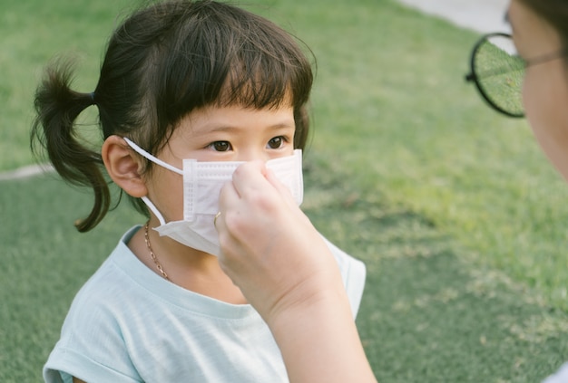 Kleine sian Mädchen und Mutter tragen Maske zum Schutz von pm2.5 und Coronavirus. Luftverschmutzung pm2.5 und Coronavirus-Konzept