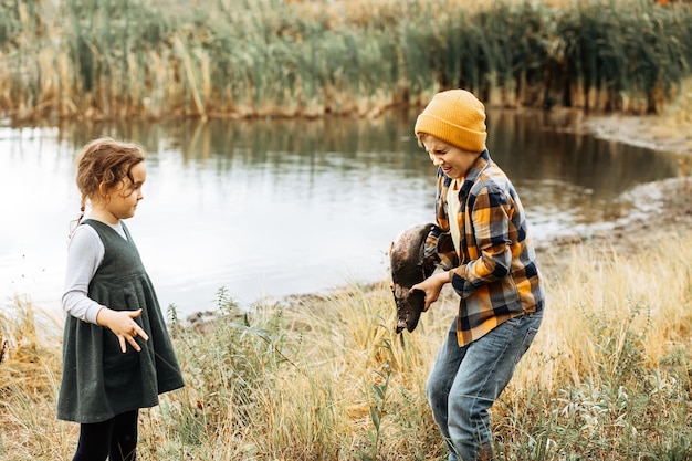 Kleine süße Mädchen und Jungen fangen einen Fisch im See, Fluss oder Teich. Lustiges Kind möchte einen Fisch in den Händen halten